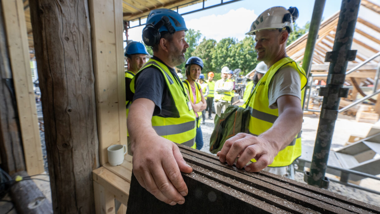 To menn og en veggplate av naturmateriale.